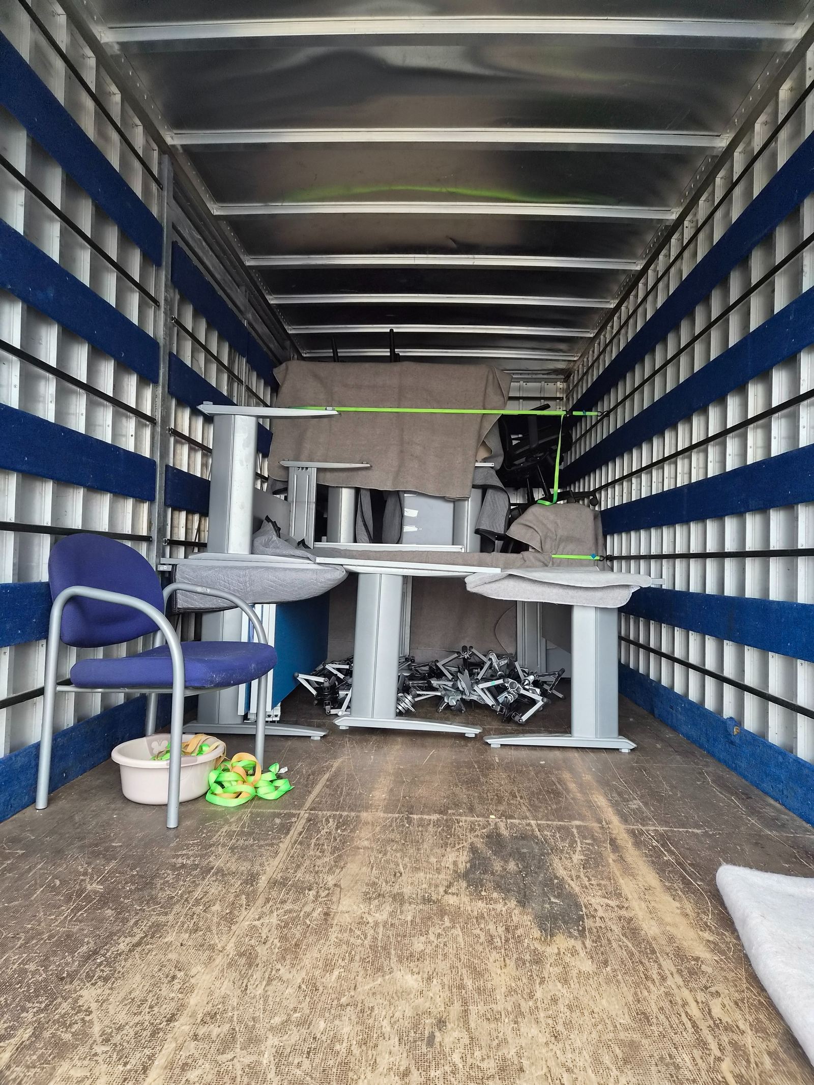 Office desks and chairs blanket-wrapped and strapped for transit during a Waikato commercial move